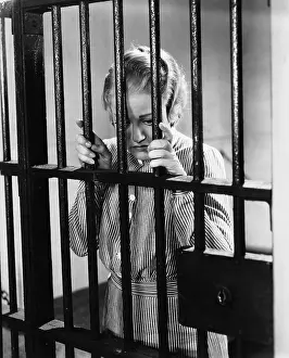 Lamenting: Young woman standing in a prison cell