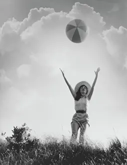 Freizeit: Young woman throws beach ball