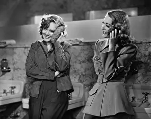 Bathrooms: Two young women leaning against a bathroom sink