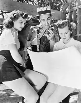 Blonds: Two young women and a man looking at architectural plans